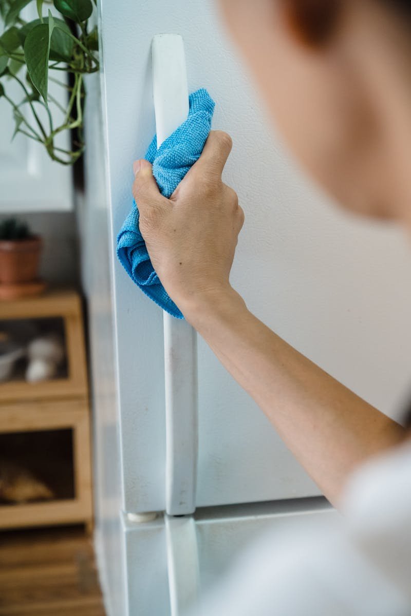 Close-up of a Person Wiping the Handle of a Cabinet